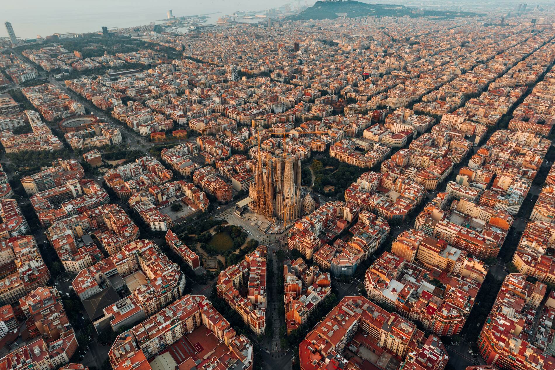 Aerial view of Barcelona's Eixample district, a dense organised city grid with the Sagrada Família visible within it